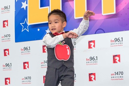 6 歲的 Howard 江慶浩胸前掛上大蘋果，跳唱幾年前曾紅遍大江南北的《小蘋果》。